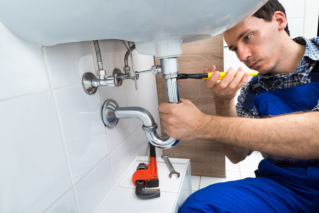 Handling maintenance requests, close-up of plumber working.